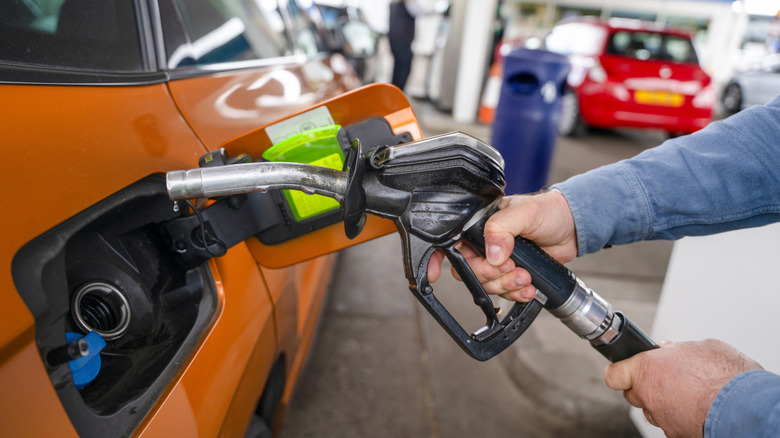 A person filling up a car with gas at a gas station.