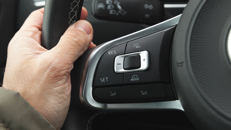 Close-up of a car's steering wheel with cruise control button.