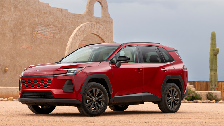 front three quarters shot of a red Toyota RAV4 parked in front of a cactus and a tan building in the desert