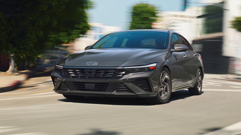A front three quarters shot of a gray Elantra hybrid driving around a corner in a city