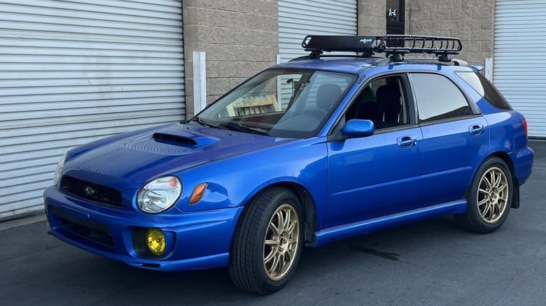 Front three quarters shot of my brother's blue 2003 Subaru WRX wagon parked in front of garage doors