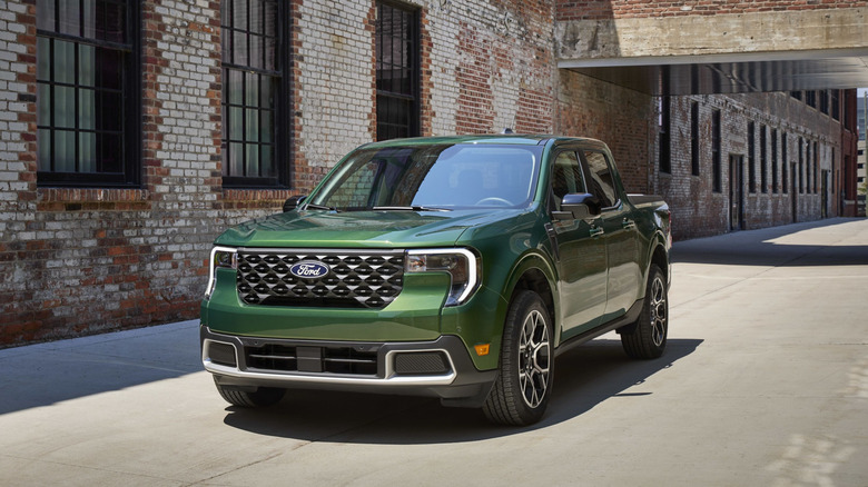 A green 2025 Ford Maverick in front of a brick building.