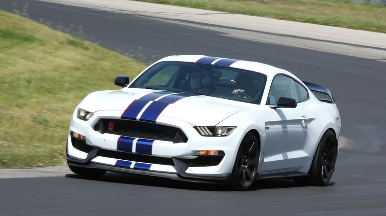 A white Ford Mustang Shelby GT350 cornering on a track.