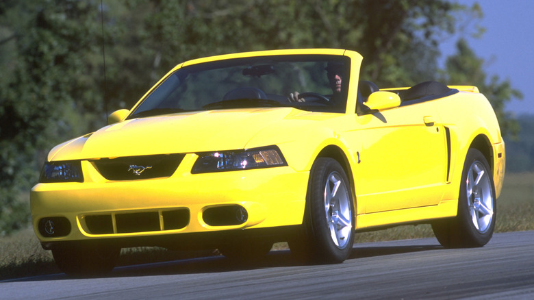 A yellow SVT Cobra being driven down a road.