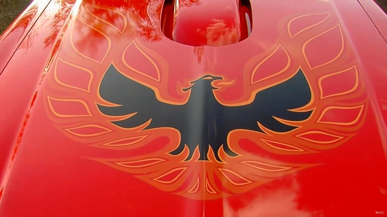 A closeup of the Rising Phoenix/Firebird/Screaming Chicken on the hood of a red 1974 Pontiac Trans Am Super Duty 455