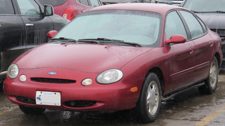 A red 1997 Ford Taurus in a parking lot