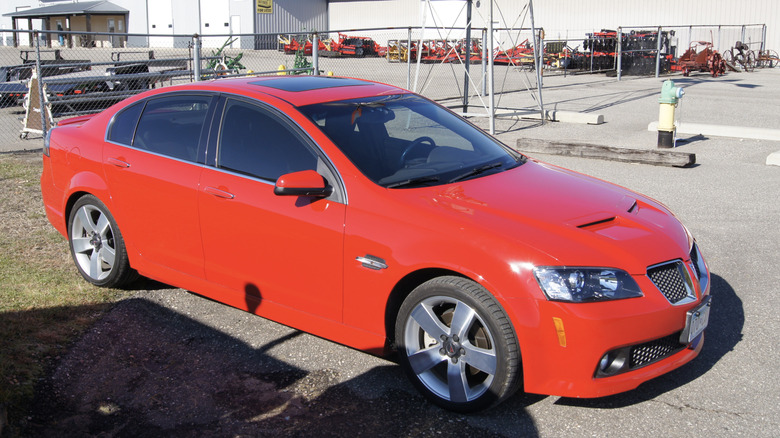 A red 2008 Pontiac G8 parked behind a warehouse