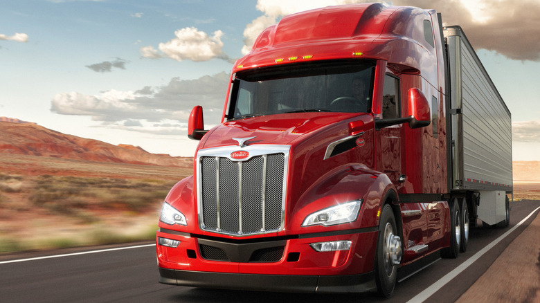 A red Peterbilt 579 pulling a trailer on the highway