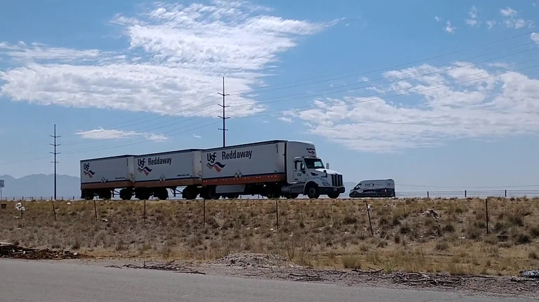 A Reddaway triple trailer semi truck being driven on the West Coast