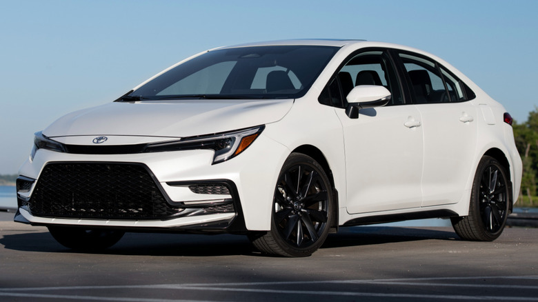 Wind chill pearl 2025 Toyota Corolla parked on a paved surface next to a body of water