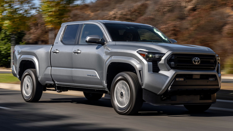 2025 Toyota Tacoma SR5 driving down a road next to a hillside