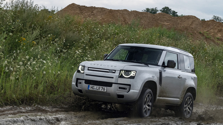 Ahlbeck, Germany - 26th July, 2022: Land Rover Defender driving on muddy road. This vehicle is used to get in extremely hard areas.