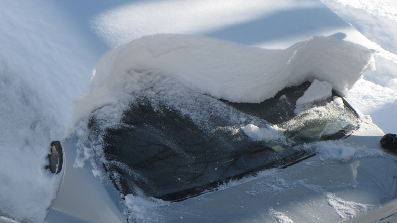 A large amount of snow on the roof of a car.