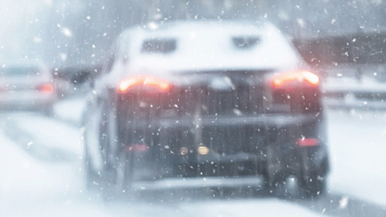A black car with an obstructed rear window from snow coverage.