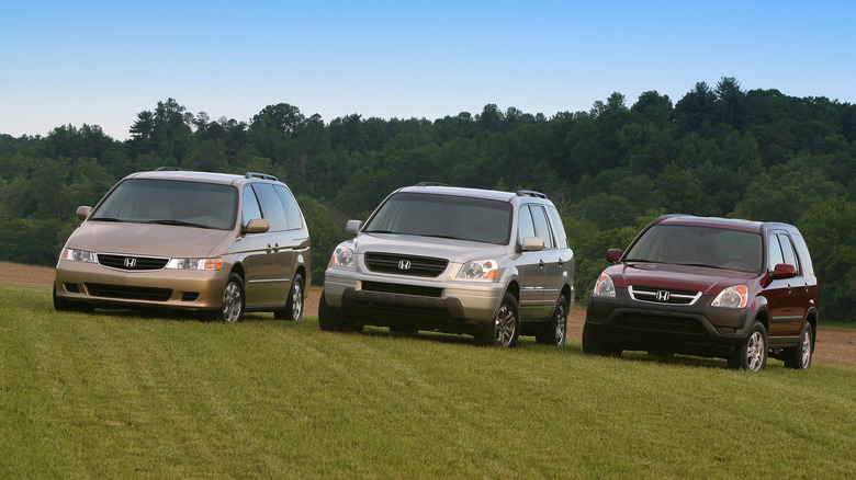 A 2002 Honda Odyssey, a 2003 Honda Pilot, and a 2002 Honda CR-V sit side-by-side on a grassy hill.