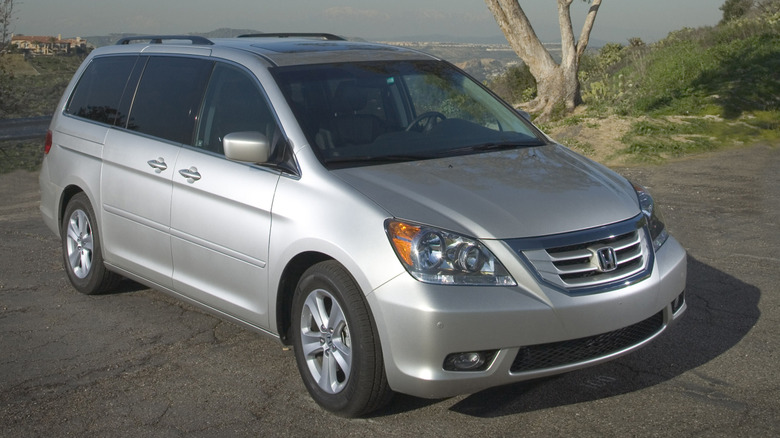 A silver 2010 Honda Odyssey sits parked on a hill.