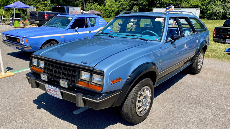 A blue 1981 AMC Eagle station wagon in a parking lot at a car show