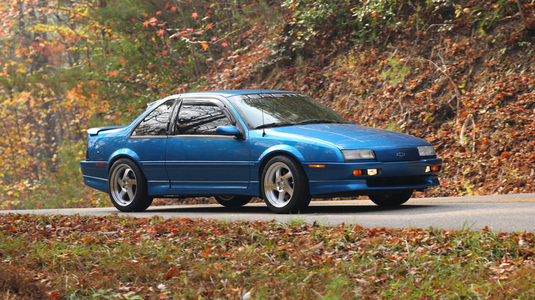 A blue Chevrolet Beretta GTZ driving down a forest road
