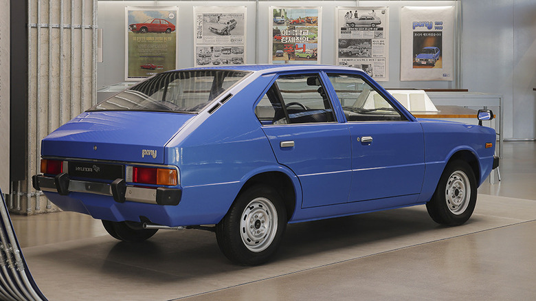 Vintage blue Hyundai Pony hatchback seen in right rear three-quarter view in a museum