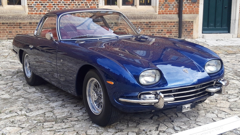 Blue Lamborghini 350 GT sports car seen in right front three-quarter view parked on a cobbled courtyard