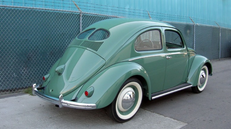 Pale green 1949 Volkswagen Type 1 Beetle seen in right rear three-quarter view parked outside by a chain link fence