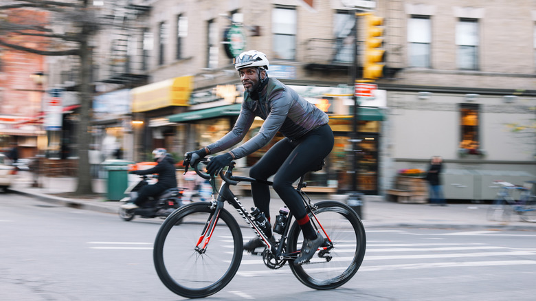 Black male cyclist riding through Brooklyn, New York. He is wearing cycling gear, going for a training ride or commuting in style, on a sunny Autumn day.