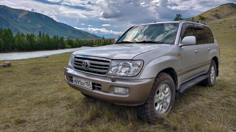Altai, Russia - July 26, 2024: Legendary suv car Toyota Land Cruiser 100 in Altai mountains grassland on the bank of Chya river.