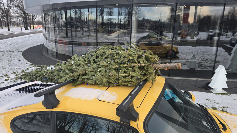 Wroclaw, Poland - January 9th 2026 - Picture of Vintage yellow Porsche 911 with black spoiler on snow and Christmas tree on roof  by: Miroslaw Durma