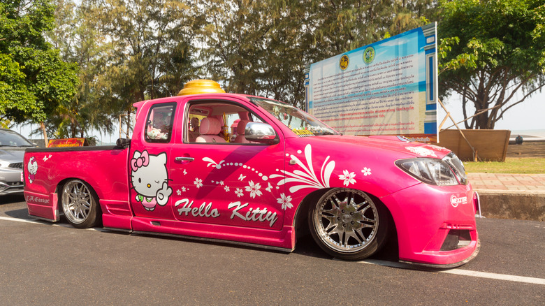 Car Tuning. Toyota Hilux Vigo Champ in pink color, Lexus logo, lowered suspension. Lowrider Toyota with 20 inch chrome wheels. Body kit, front and rear bumpers, side skirt