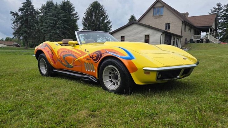 A yellow and orange C3 Corvette parked in a grass yard