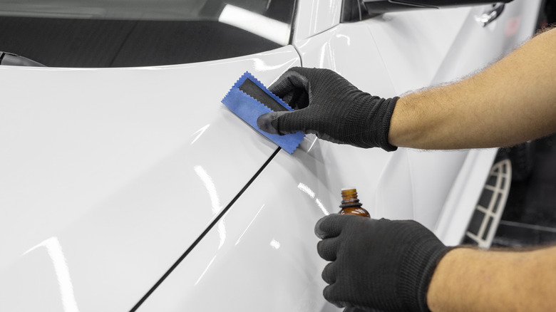 A professional detailer applying a nano-ceramic coating to a car's paint