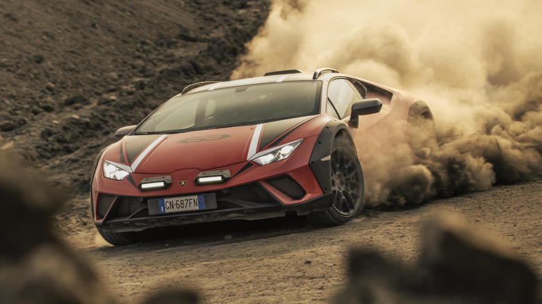 A red Lamborghini Huracán Sterrato driving off-road with clouds of dirt flying behind it