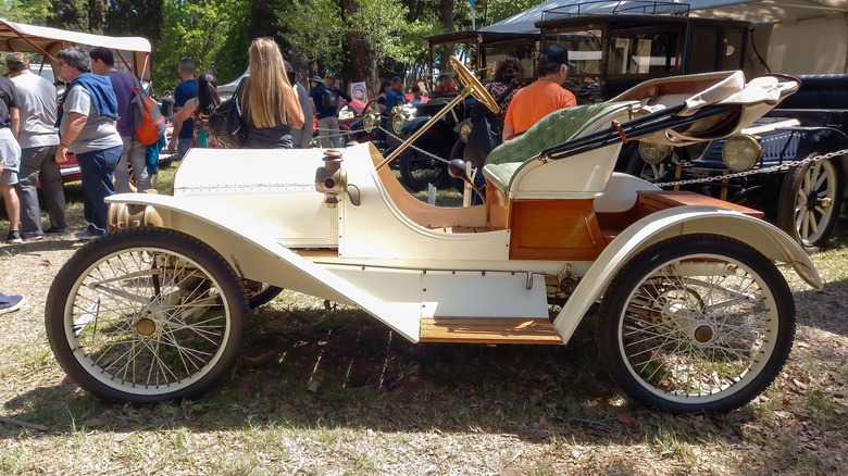 A white 1908 Metz Plan Roadster outdoors at the Autoclásica 2022 show.