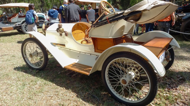 A rear 7/8 view of a white 1908 Metz Plan Roadster at Autoclásica 2022.
