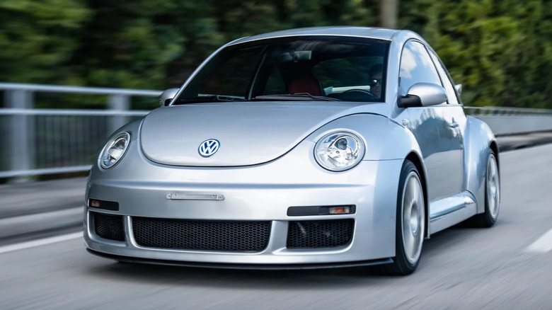front three-quarters shot of the silver Beetle RSi driving across a bridge with trees in the background
