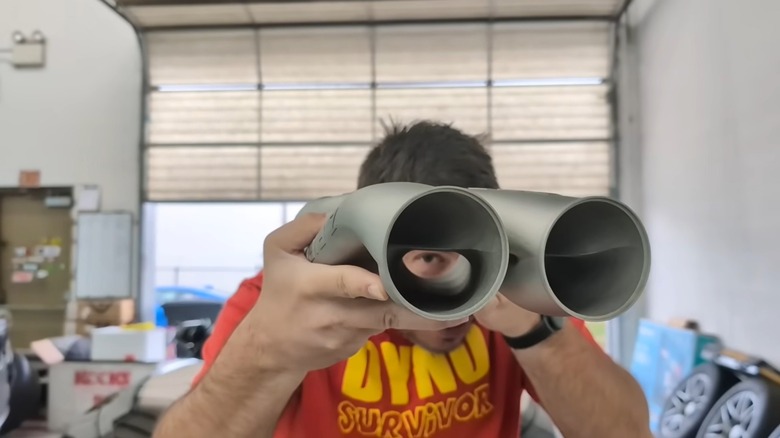 A YouTuber with Complete Street Performance holds up a Formula Z Performance Z-pipe so viewers can look through it