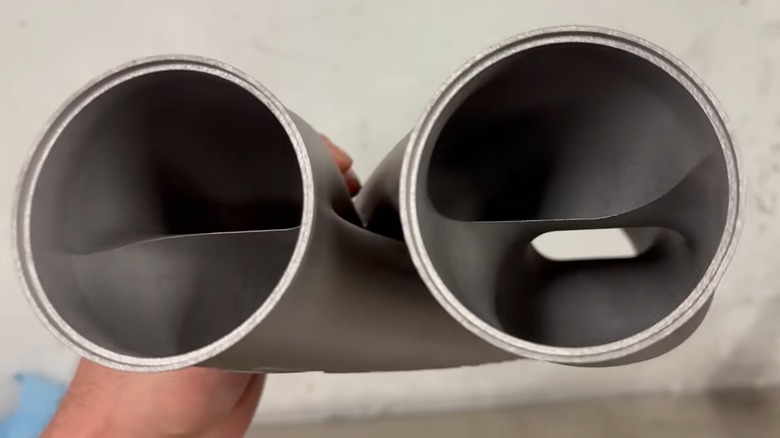 A YouTuber holds up a Formula Z Performance Z-pipe so viewers can look through the channels