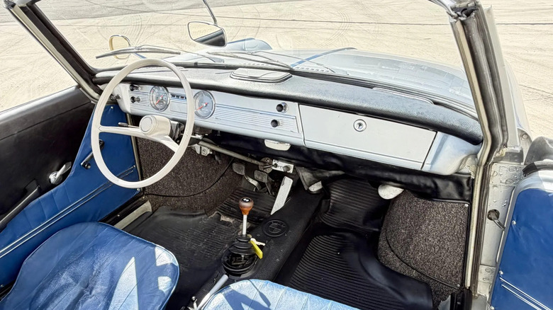 An overhead look at the blue vinyl front seats and silver dashboard of the car