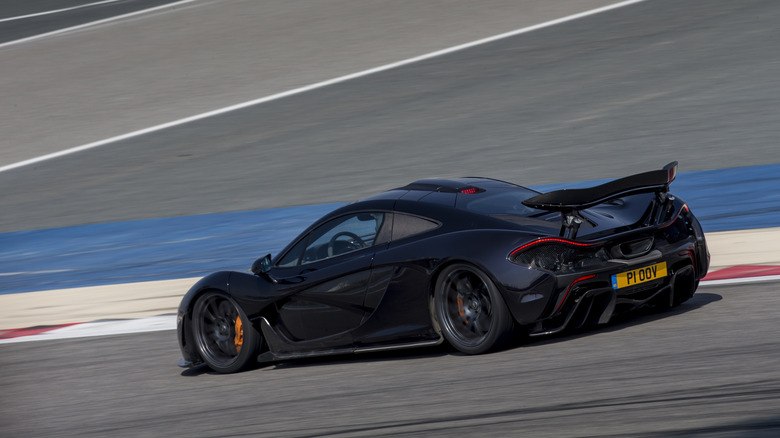 Rear 3/4 view of a black McLaren P1 on track.
