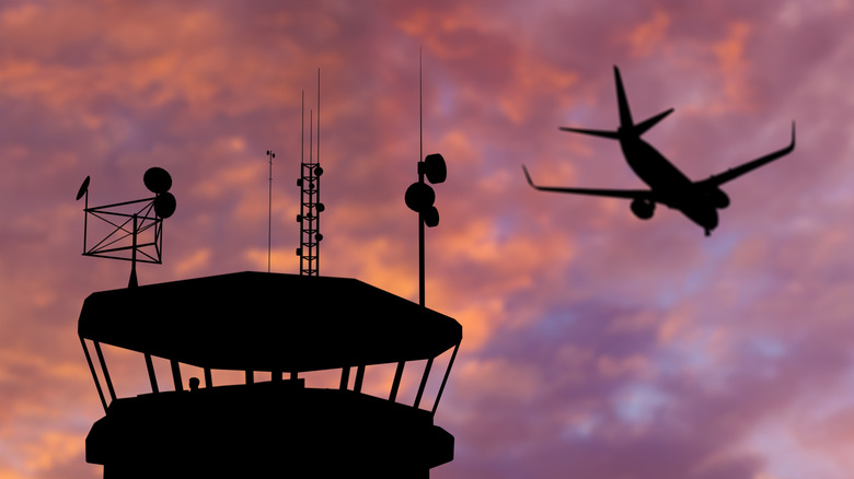 An airplane taking off and air traffic control tower in silhouette