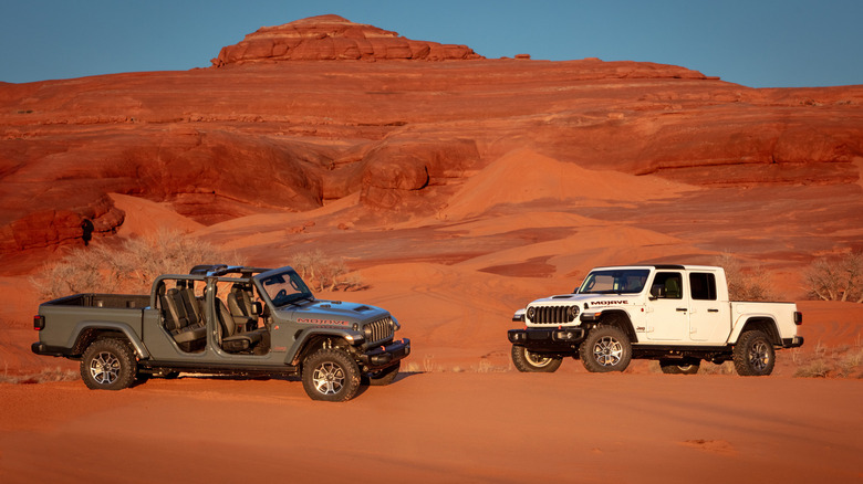 A pair of 2026 Jeep Gladiator Mojave X SUVs, one with doors and tops removed, parked in rocky desert
