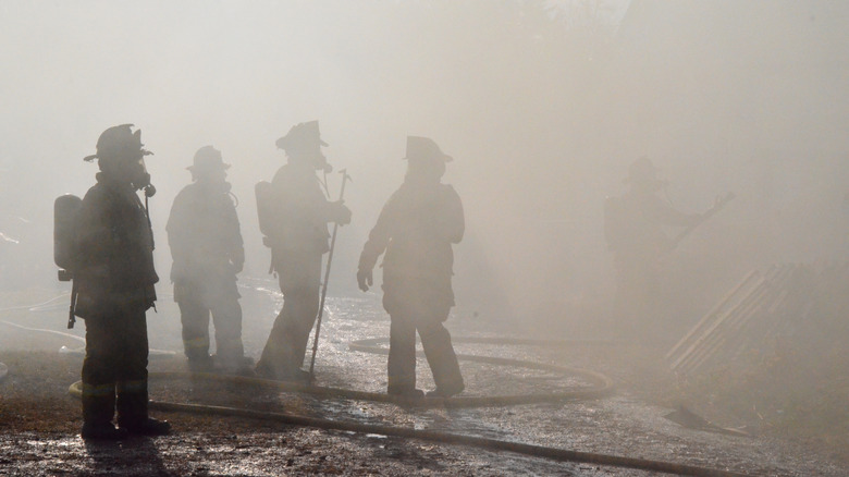 A group of fire fighters in rubble and smoke after extinguishing fire