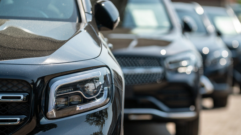 A lineup of black Mercedes-Benz SUVs with the first one in focus and the rest blurred