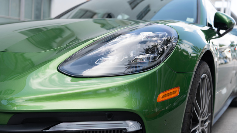 A close-up view of the left headlight and front section of a green Porsche Panamera