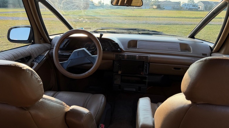 The view from the second row of seats in the Silhouette showing its beige interior parked in a grassy field