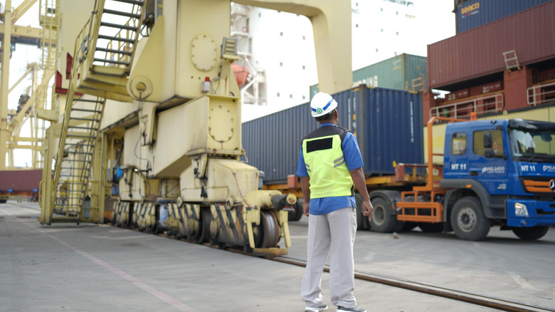 A dockworker at a port turned toward a cargo truck.