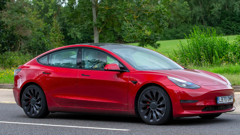 A side profile of a red Tesla Model 3.