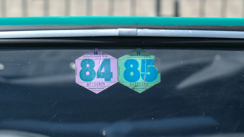 Vintage French tax stickers on the windshield of an old car.
