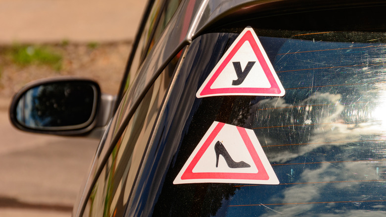 A pair of stickers on the rear windscreen of a hatchback.