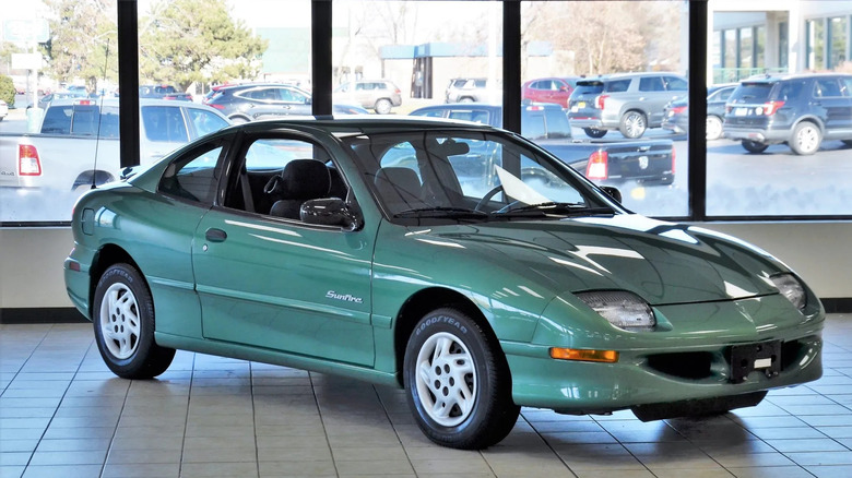Front three-quarters shot of a green Pontiac Sunfire coupe parked in a showroom